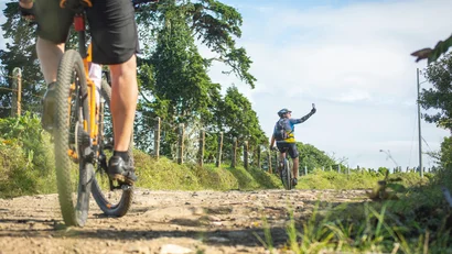 Zwei Radfahrer auf einem Schotterweg, einer macht ein Selfie