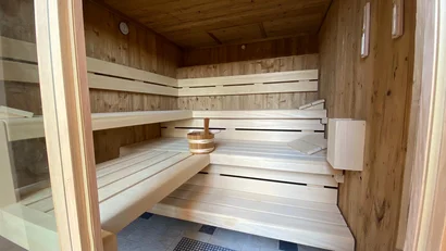 Innenansicht einer Holzsauna mit Bänken und Saunaeimer