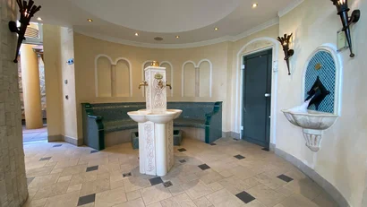 Innenraum mit verziertem Wasserbrunnen und Sitzbereich mit Mosaikfliesen