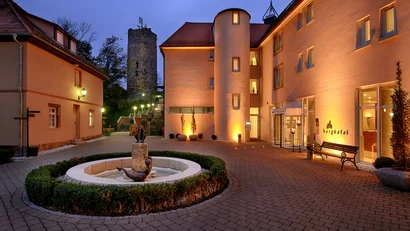 Beleuchteter Innenhof mit Brunnen und historischem Turm bei Abenddämmerung