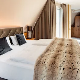 Gemütliches Hotelzimmer mit großem Bett und Bad im Hintergrund