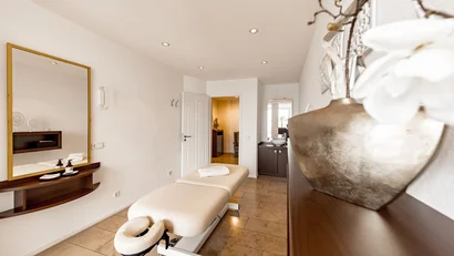 Heller Massageraum mit Liege, Spiegel und Dekoration