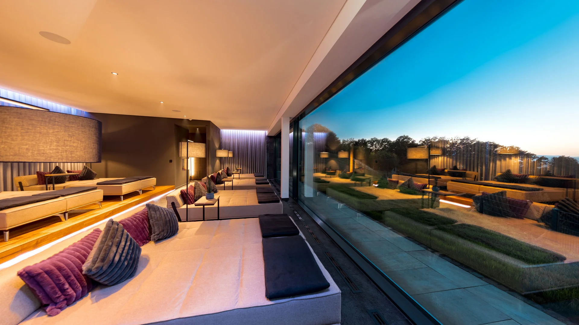 Moderne Lounge mit großen Sofas und Panoramafenster mit Ausblick auf Bäume