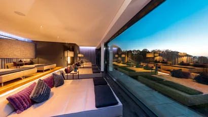 Moderne Lounge mit großen Sofas und Panoramafenster mit Ausblick auf Bäume