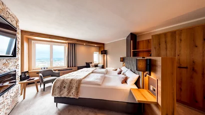 Gemütliches Hotelzimmer mit Doppelbett, Fensterblick und Holzmöbeln