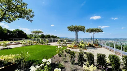 Moderne Dachterrasse mit Pflanzen und Blick auf die Stadt unter blauem Himmel