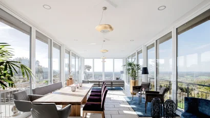 Heller Wintergarten mit großem Esstisch, Stühlen und Panoramablick