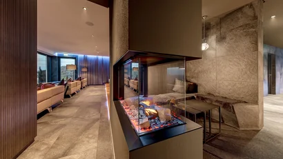 Moderner Innenraum mit gläsernem Kamin und Sitzbank mit Kissen