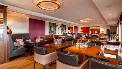 Modernes Restaurant mit Holztischen, Lederstühlen und dekorativen Hirschbildern