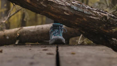 Wanderer mit Wanderschuhen über Holzweg im Wald